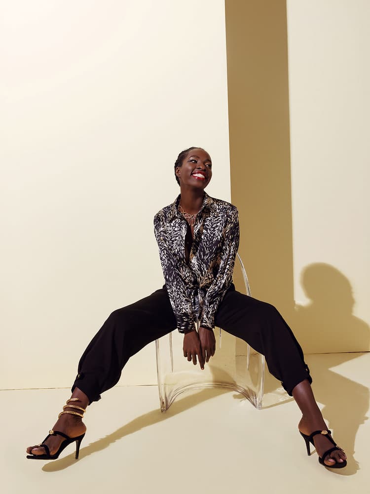A model in a dynamic pose wearing a black and white brush-stroke print silk button-down shirt paired with matching silk joggers.