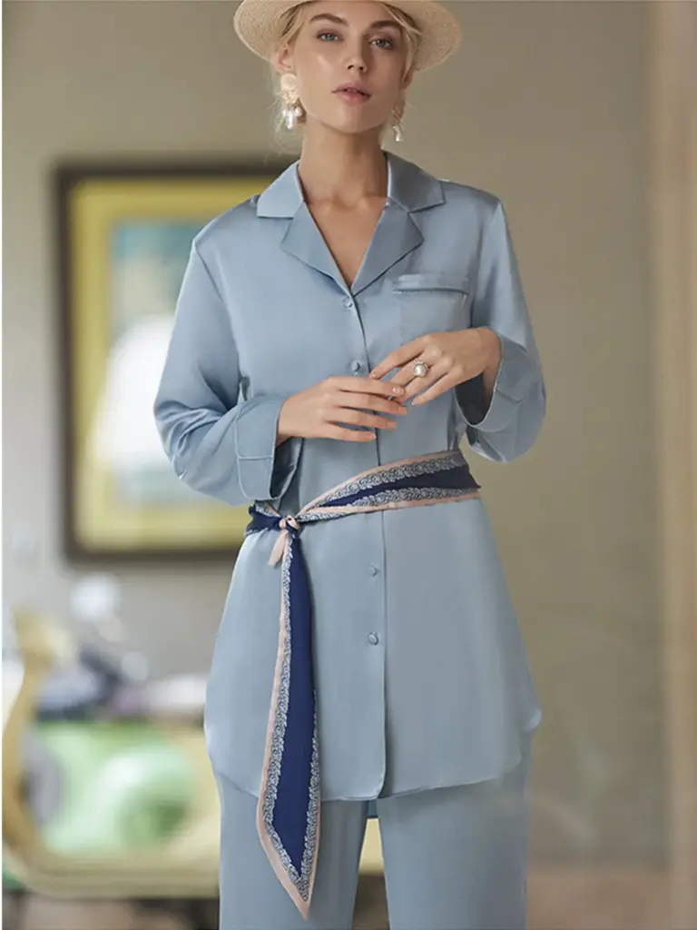 A model wearing a light blue silk pajama-style shirt accented with a navy blue patterned silk belt.