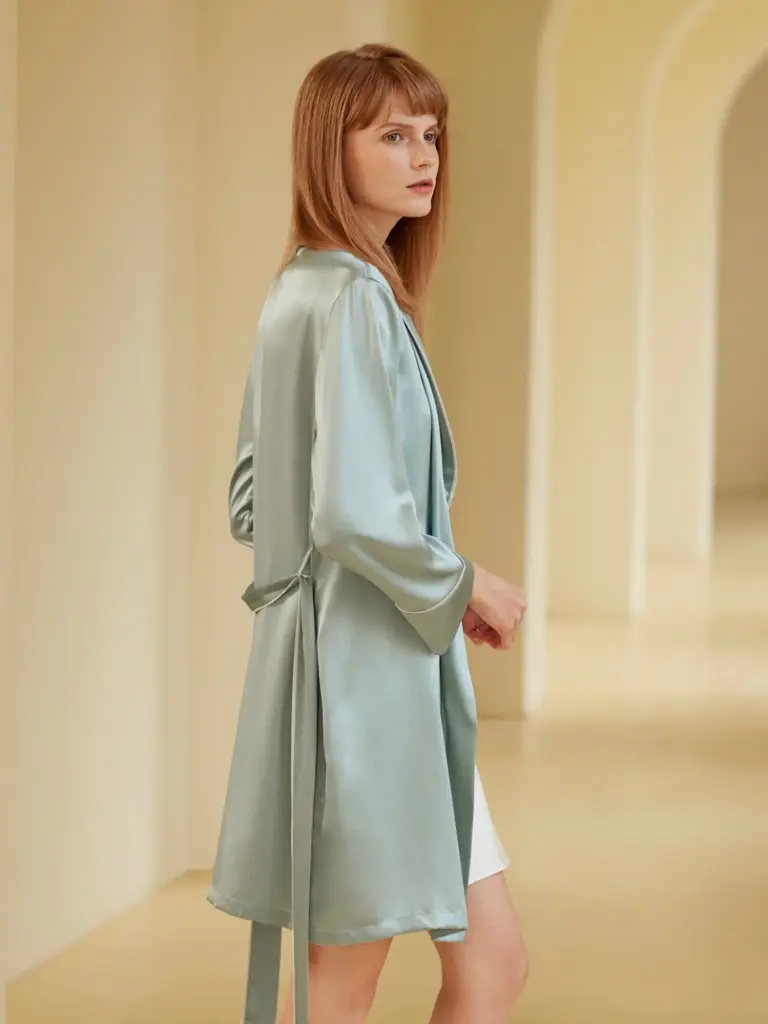 A model in a pale blue silk lounge gown, showing the elegant side profile and premium fabric sheen.