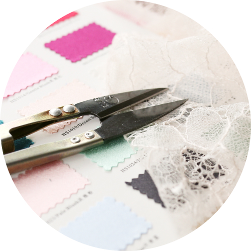 Fabric swatches and scissors on lace fabric representing garment production and manufacturing at Passionworks